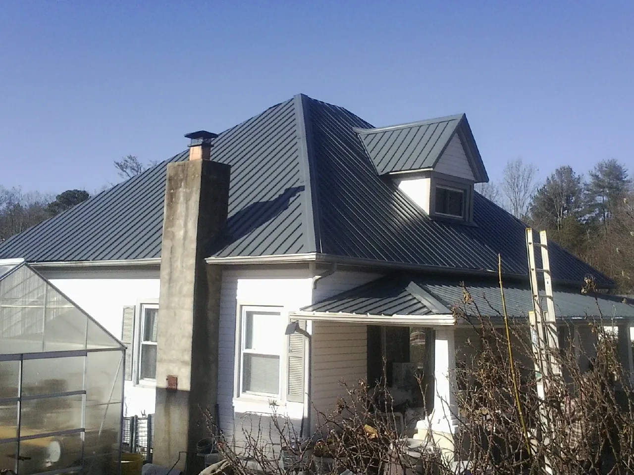 Dark blue standing seam metal roof on a white farmhouse with dormer — Slate & Tile Roof Repair by Roofing Brothers in Cloverdale