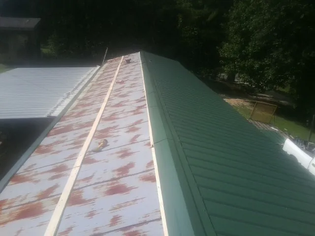 Old rusted panels beside newly installed green metal roofing — Wind Damage Roof Repair by Roofing Brothers in Cloverdale